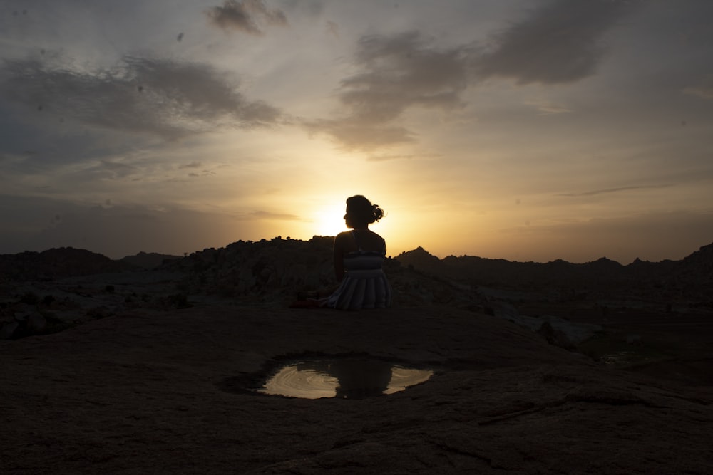 a woman standing on top of a dirt field