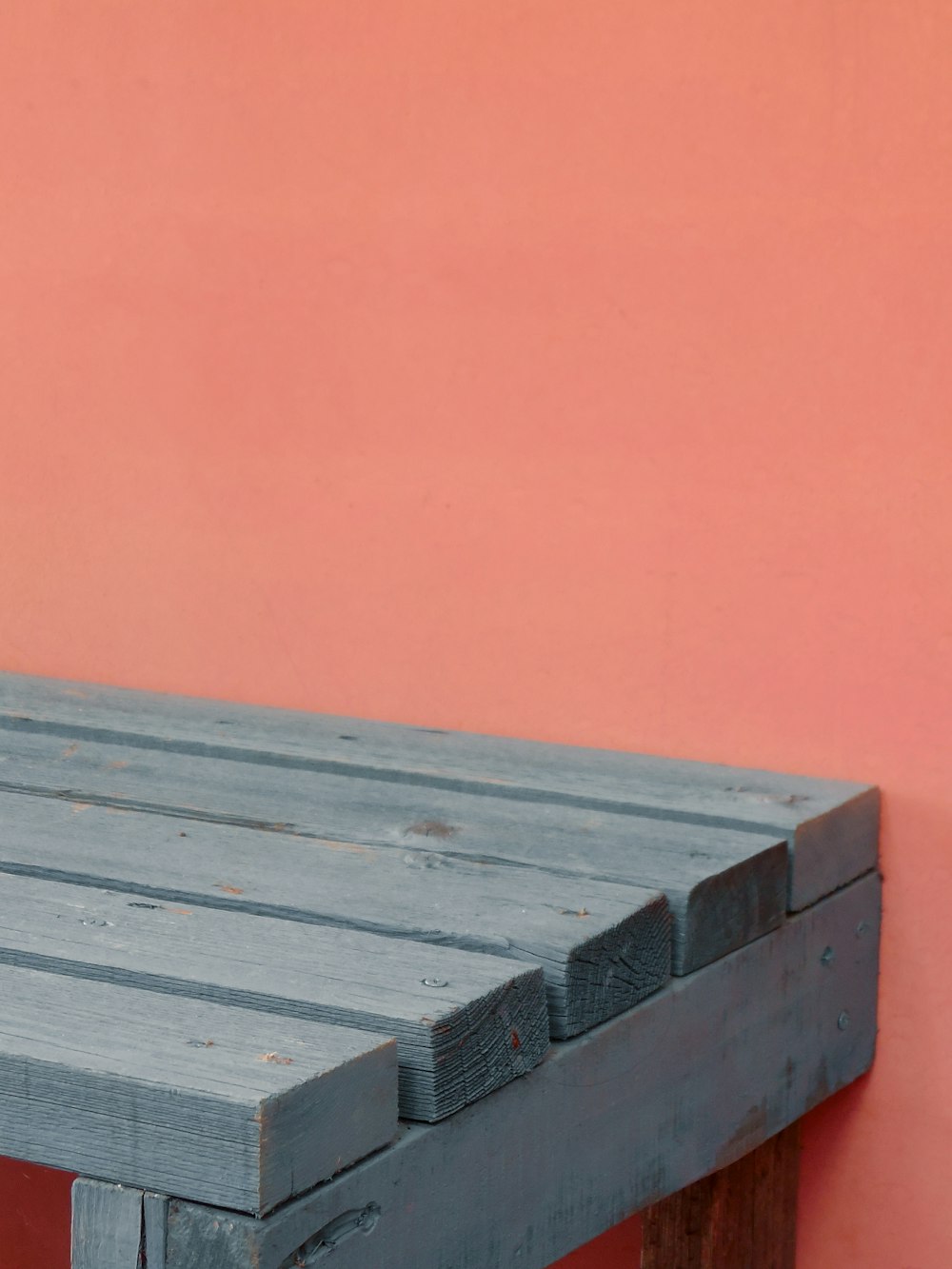 a wooden bench against a pink wall