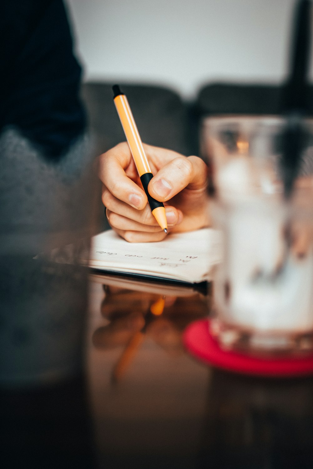 a person sitting at a table writing on a notebook