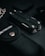 A multitool is surrounded by various dark-colored objects, including a textured black pouch. The scene is set against a dark backdrop, creating a sleek and minimalist aesthetic.