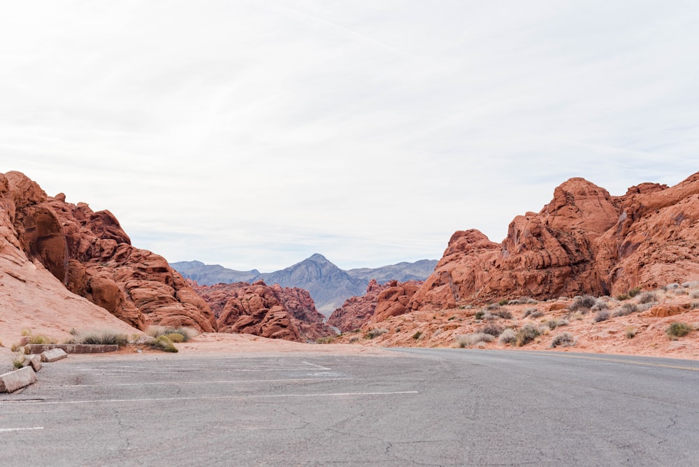 an empty road in the desert with mountains in the background