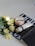 A set of skincare products including a jar of AHA scrub and a tube of cream. They are placed on top of an open black and white magazine. Beside the products, there is a bouquet of light yellow roses. The scene is set against a light background, with soft lighting highlighting the items.