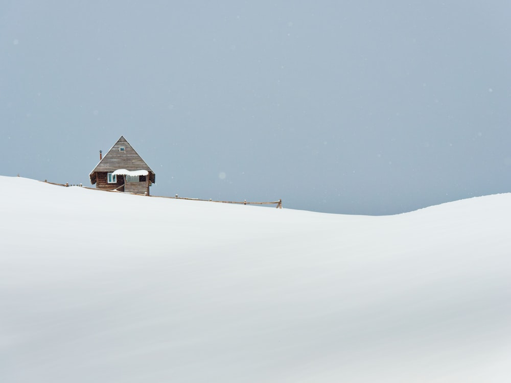 a small house sitting on top of a snow covered hill