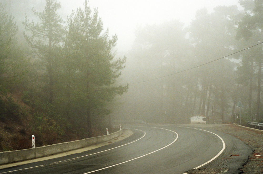 a foggy road with a stop sign on the side
