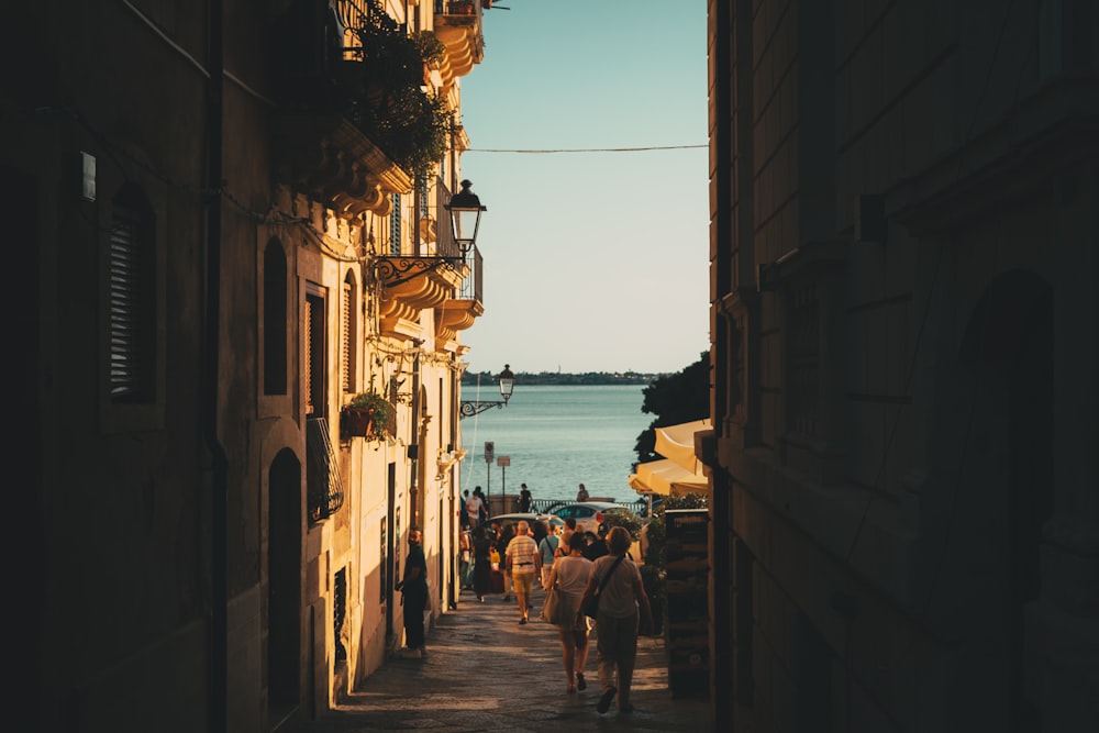 a group of people walking down a street next to a body of water