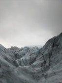 A panoramic view of rugged ice formations against a dark grey sky.