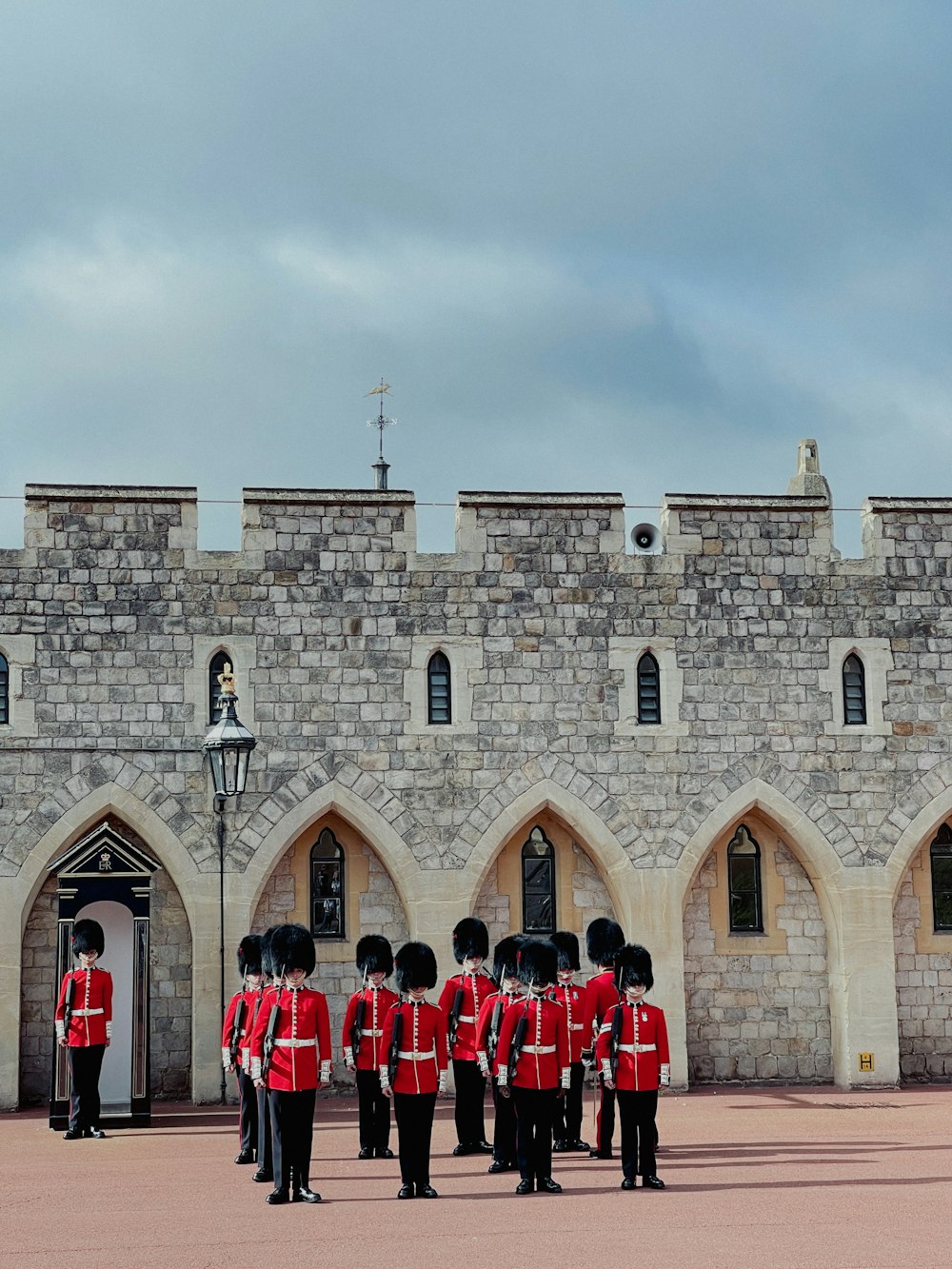 Un grupo de hombres con uniformes rojos parados frente a un castillo