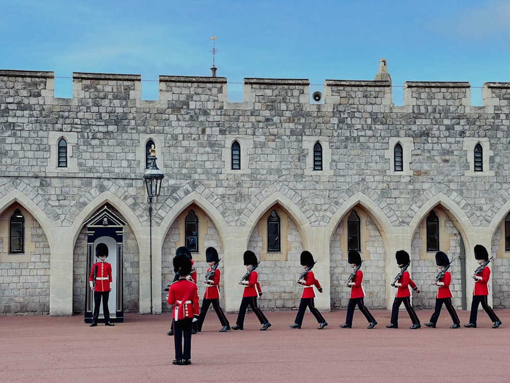 a group of men in red uniforms walking past a castle