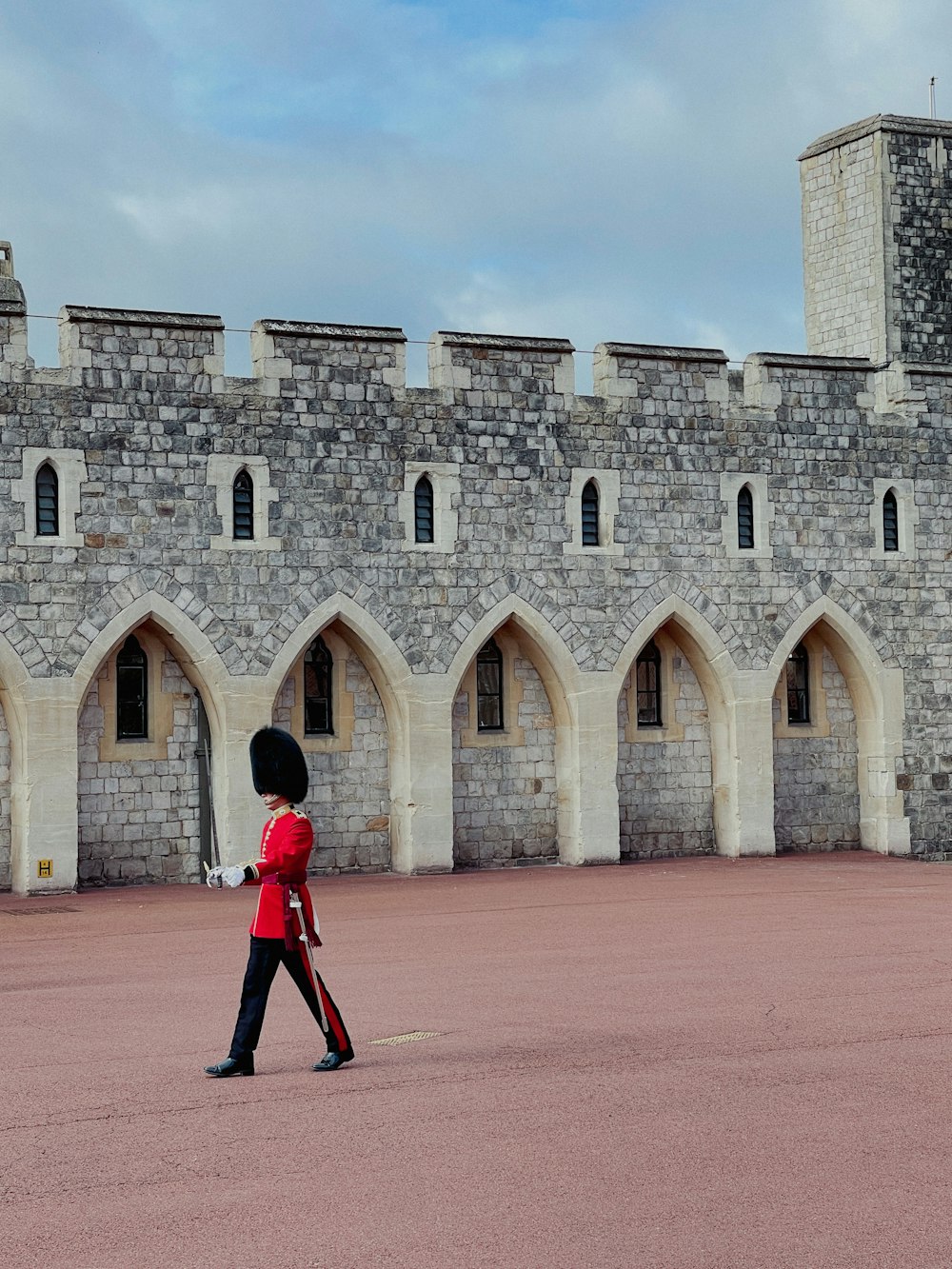 Un guardia con uniforme rojo caminando frente a un castillo