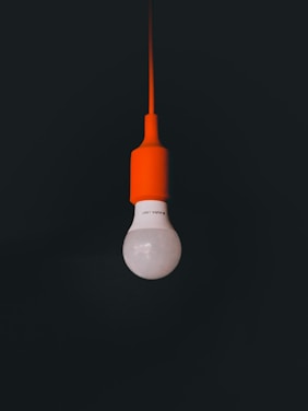 an orange light bulb hanging from a black ceiling
