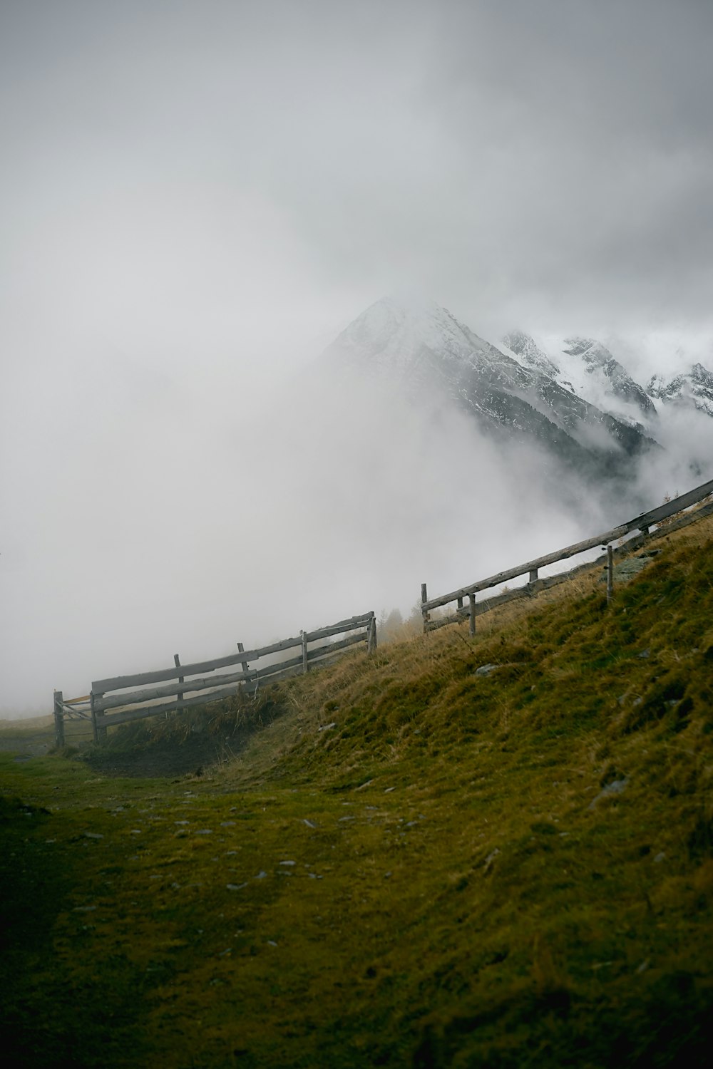 a wooden fence sitting on top of a lush green hillside