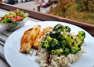 Fish and broccoli rice on a plate with a nature background