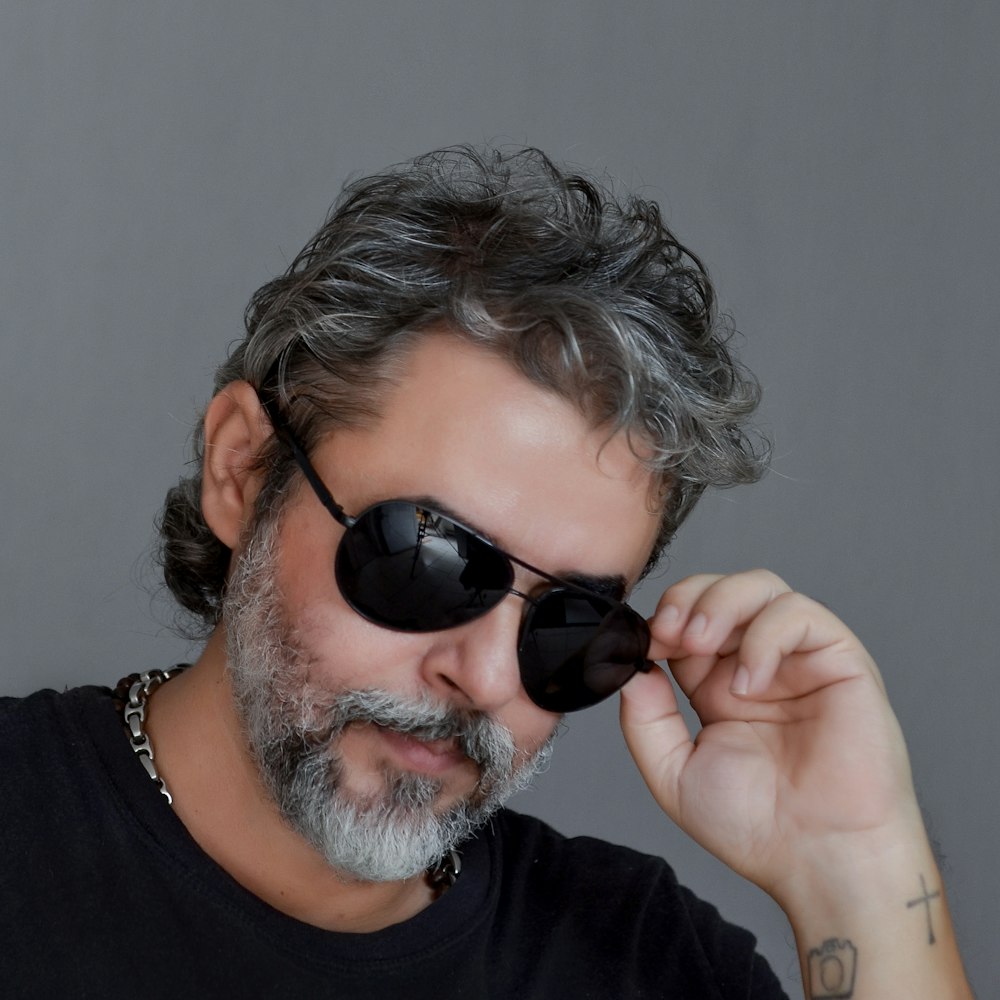 a man with a beard wearing sunglasses and a black t - shirt