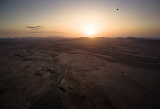 A panoramic shot of a desert sunrise with art cars and sculptures scattered across the playa.