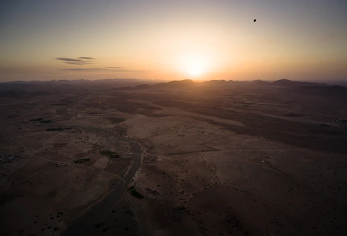 A panoramic shot of a desert sunrise with art cars and sculptures scattered across the playa.
