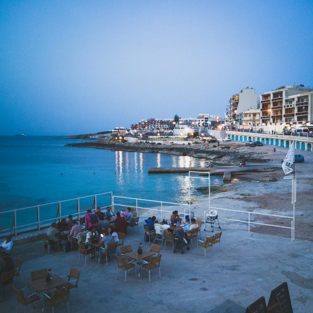 a group of people sitting at a table near the ocean