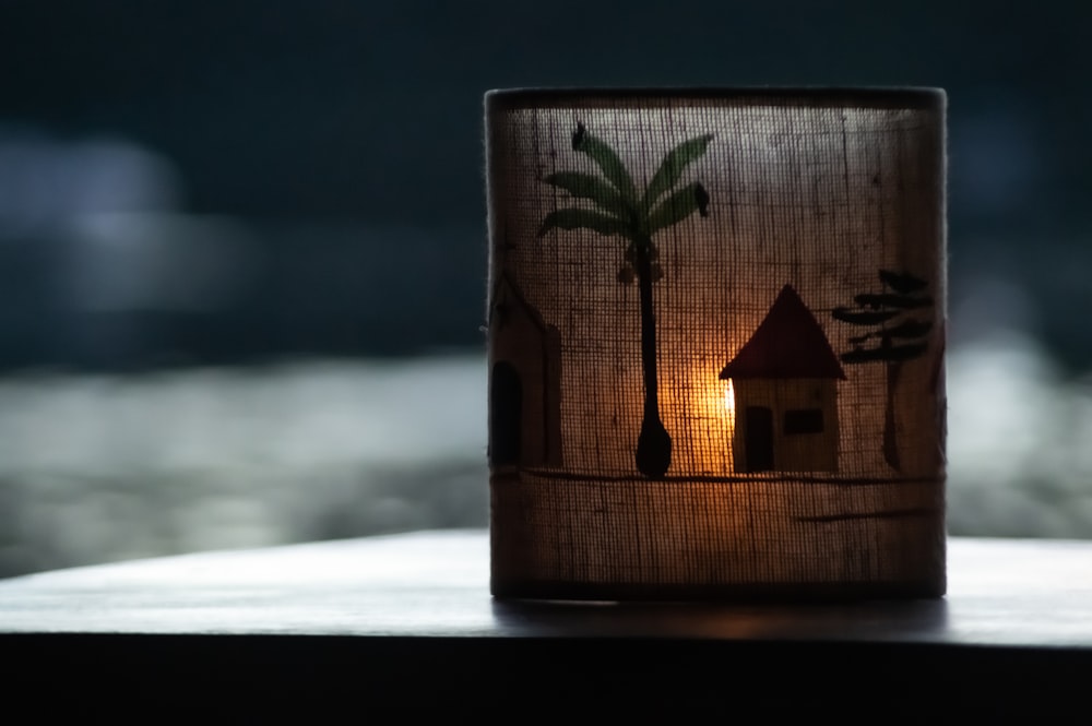 a candle holder with a house and palm trees on it