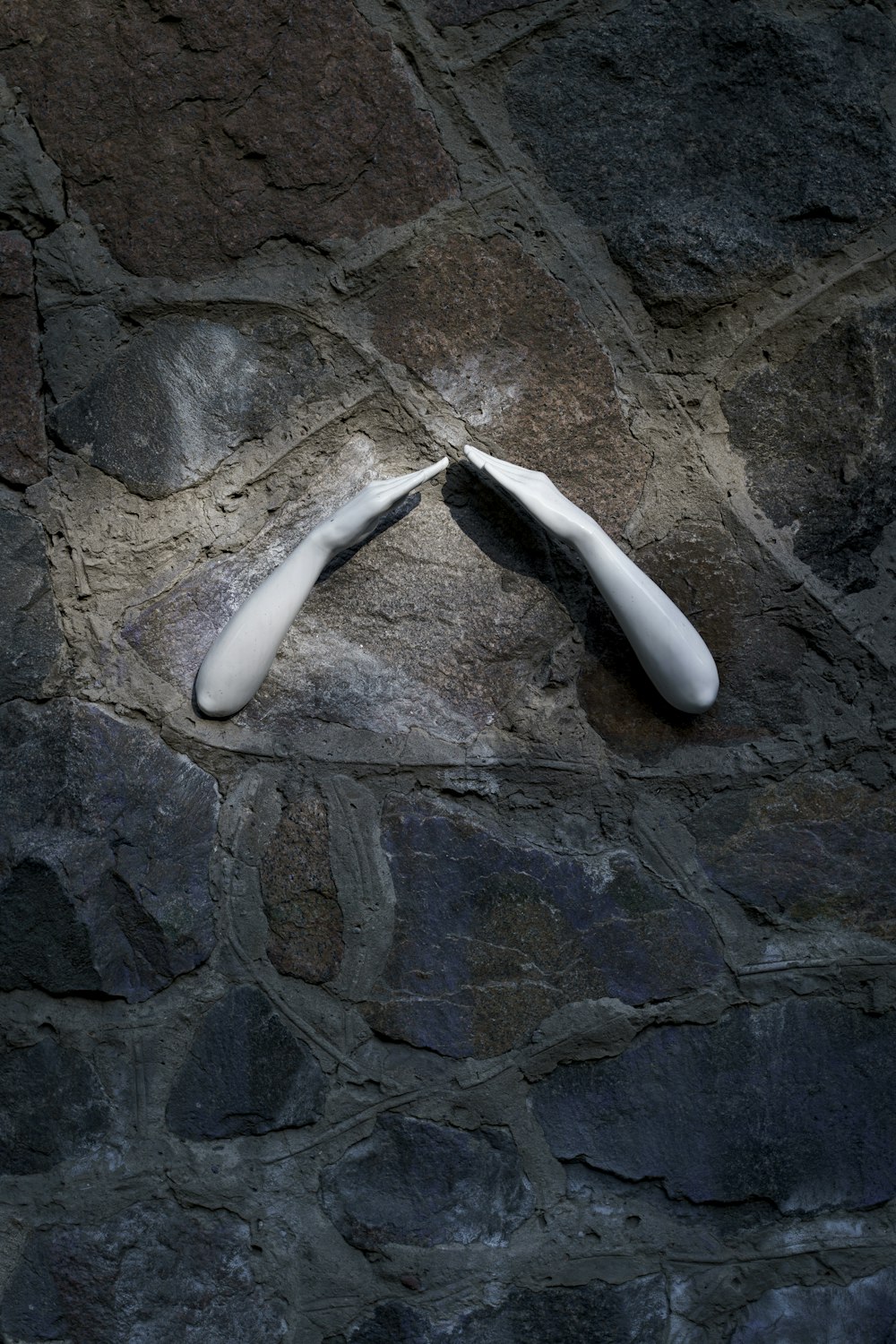 a pair of white shoes sitting on top of a stone wall