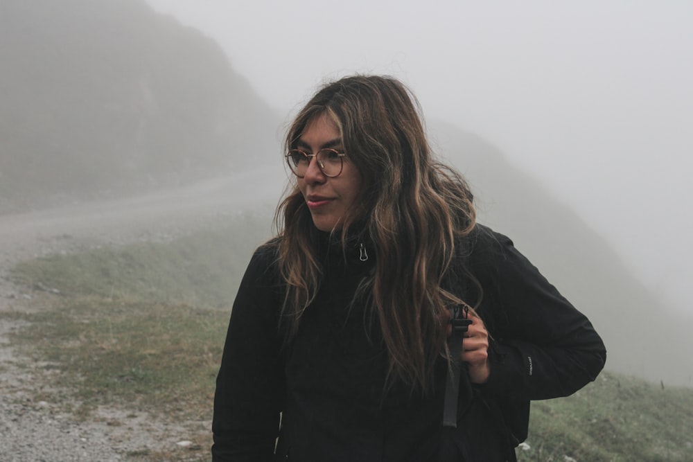 a woman with glasses standing on a foggy road