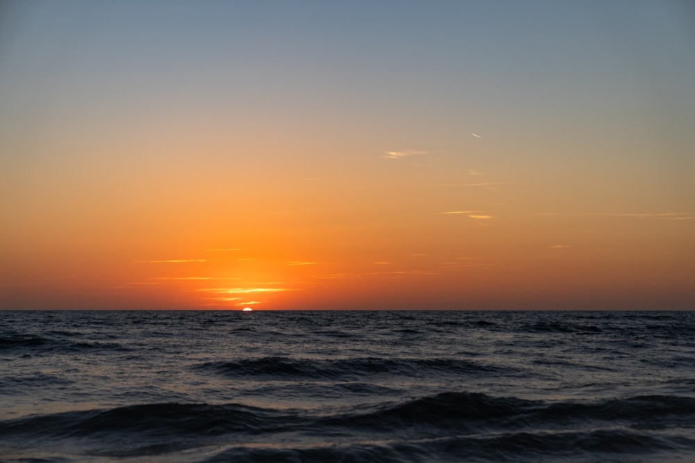 the sun is setting over the ocean on a clear day