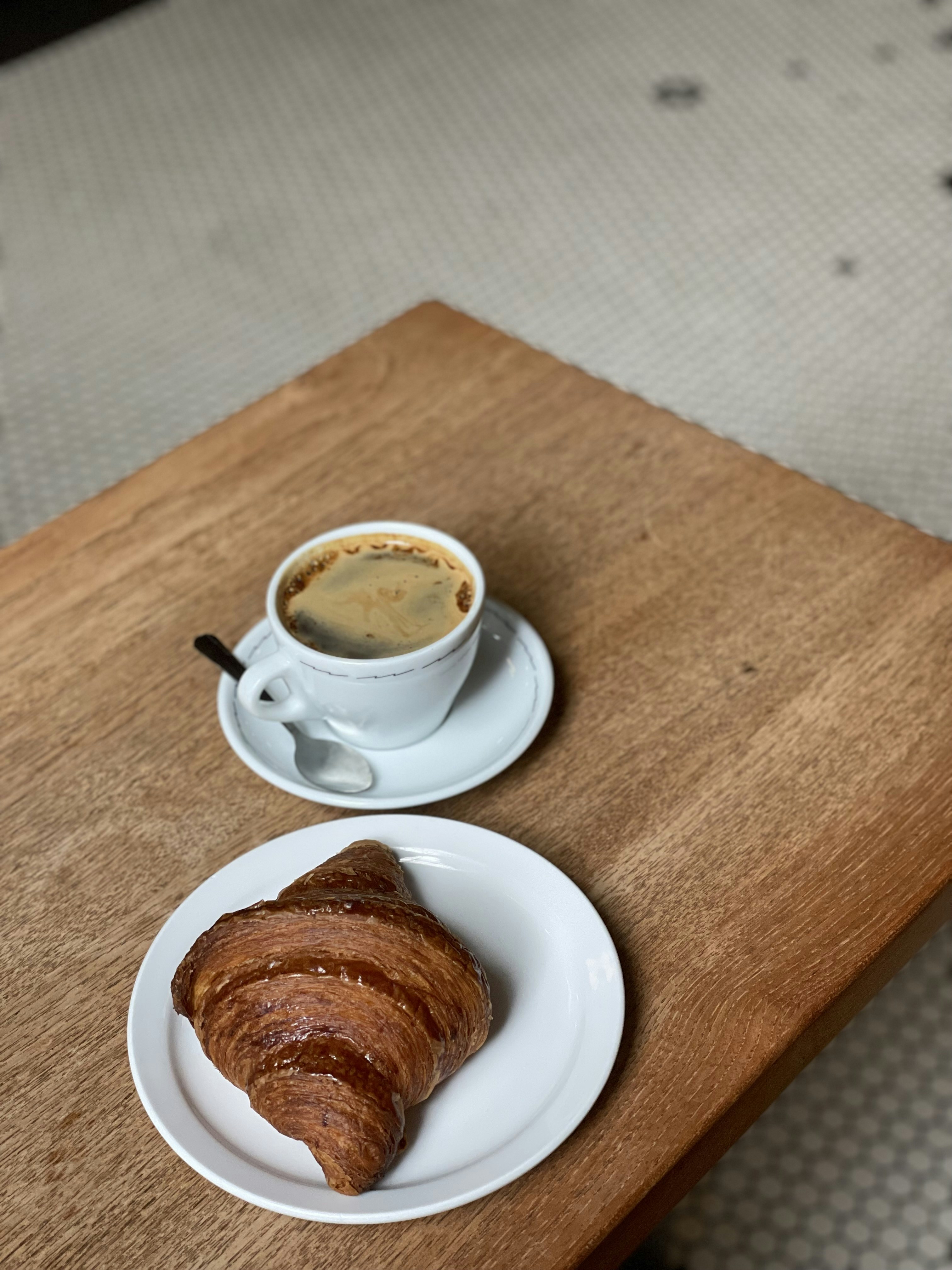 ein Croissant und eine Tasse Kaffee auf dem Tisch