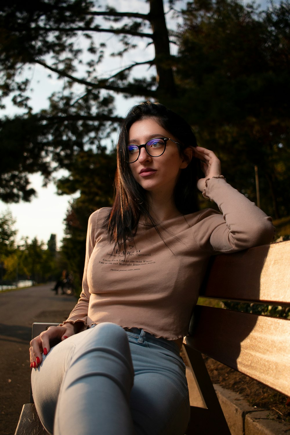 a woman wearing glasses sitting on a wooden bench