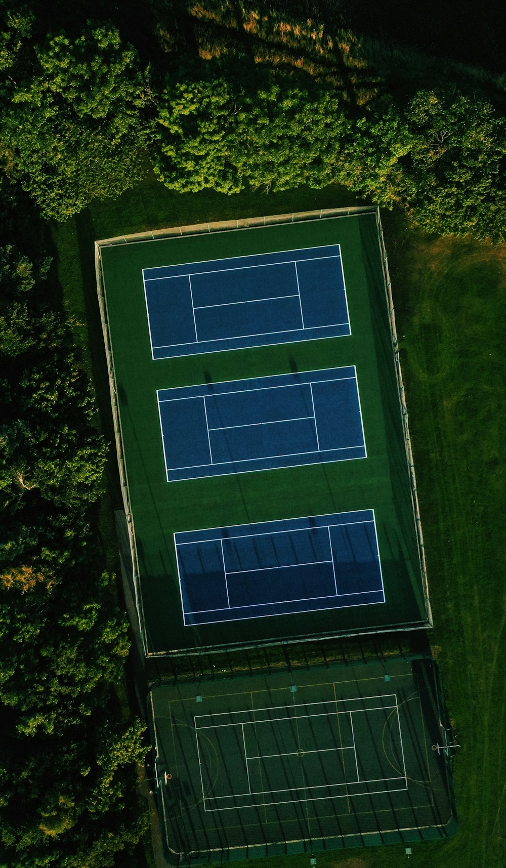 an aerial view of a tennis court surrounded by trees