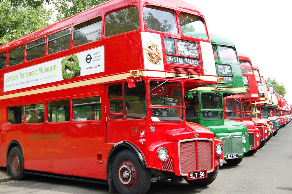 a row of red double decker buses parked next to each other