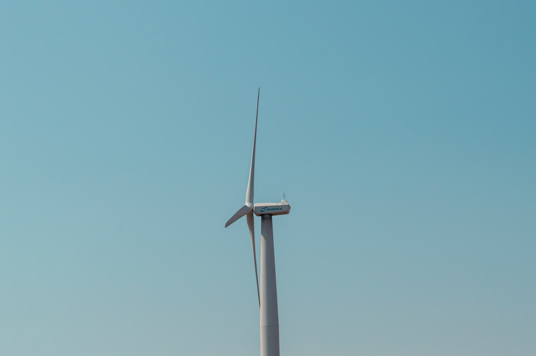 a wind turbine in the middle of a clear blue sky,