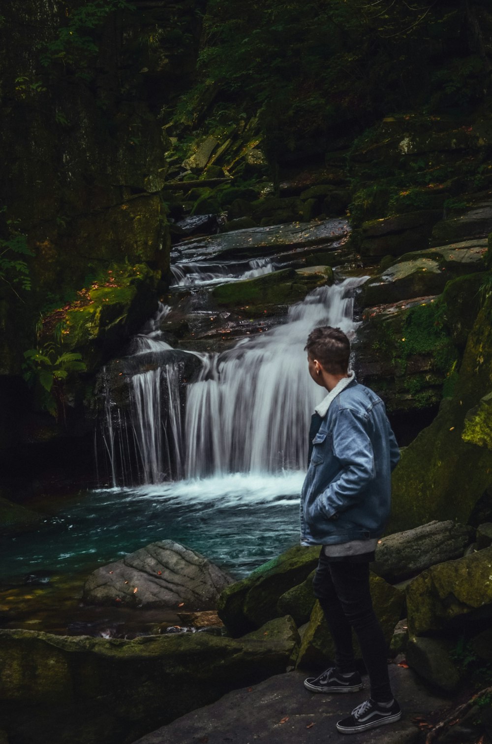 Un uomo in piedi davanti a una cascata