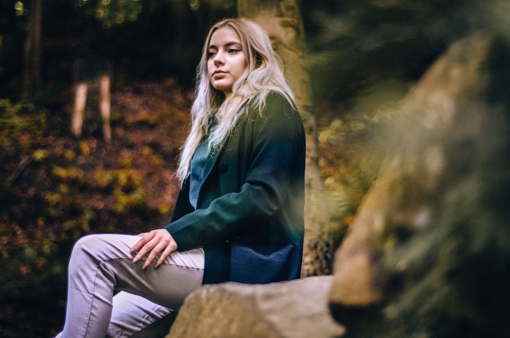 a woman sitting on a rock in the woods