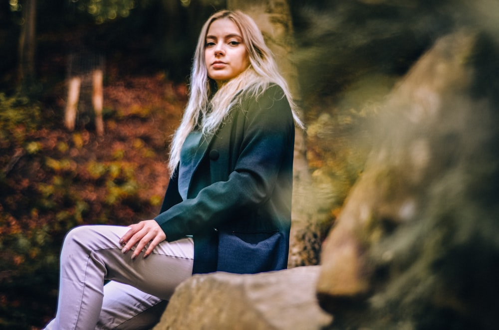 Eine Frau sitzt auf einem Felsen im Wald