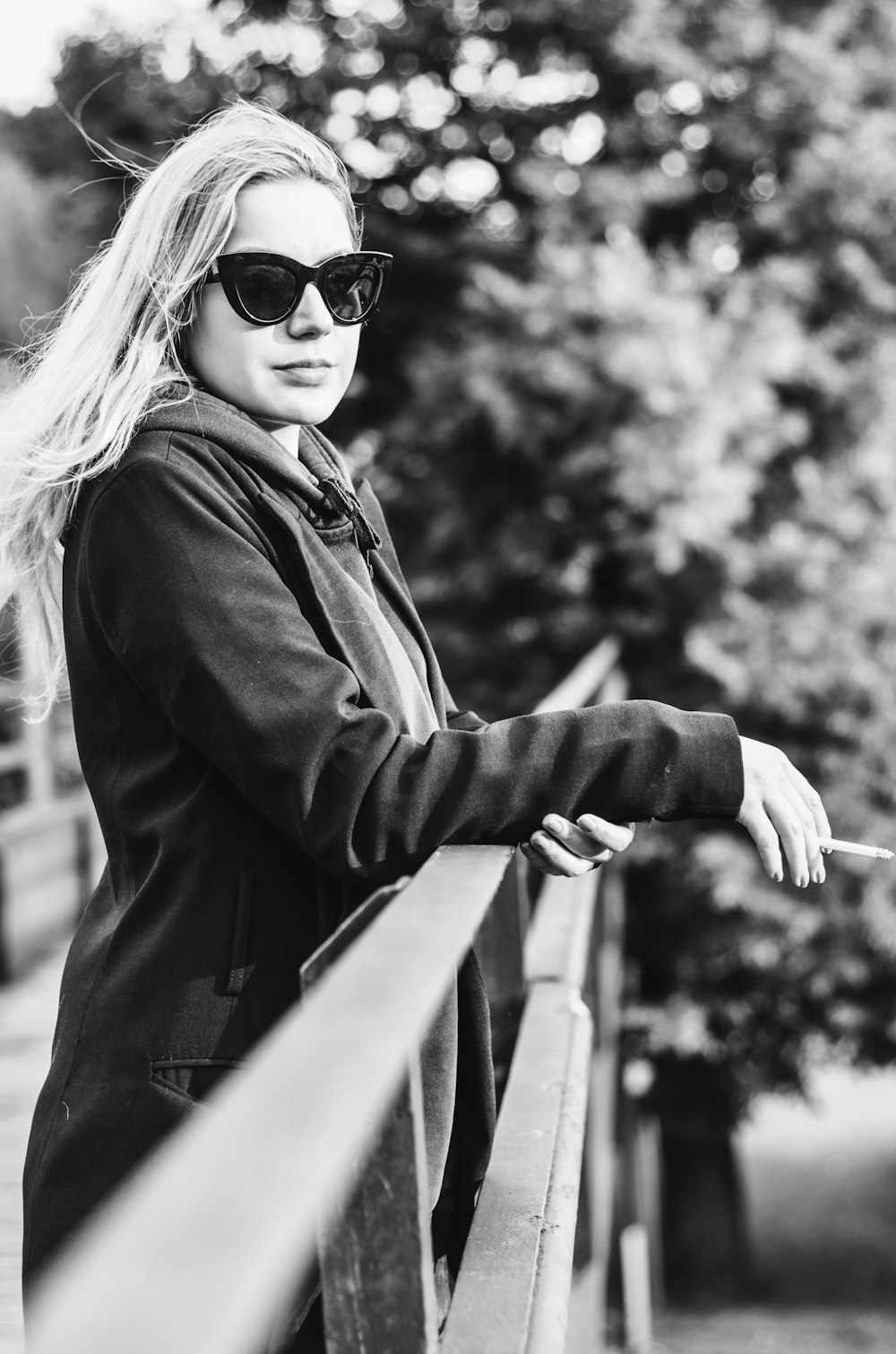 a woman wearing sunglasses leaning on a rail