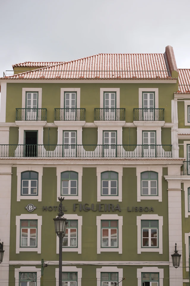 The green and white facade of the Hotel Figueira on Praça da Figueira in Lisbon's Baixa district