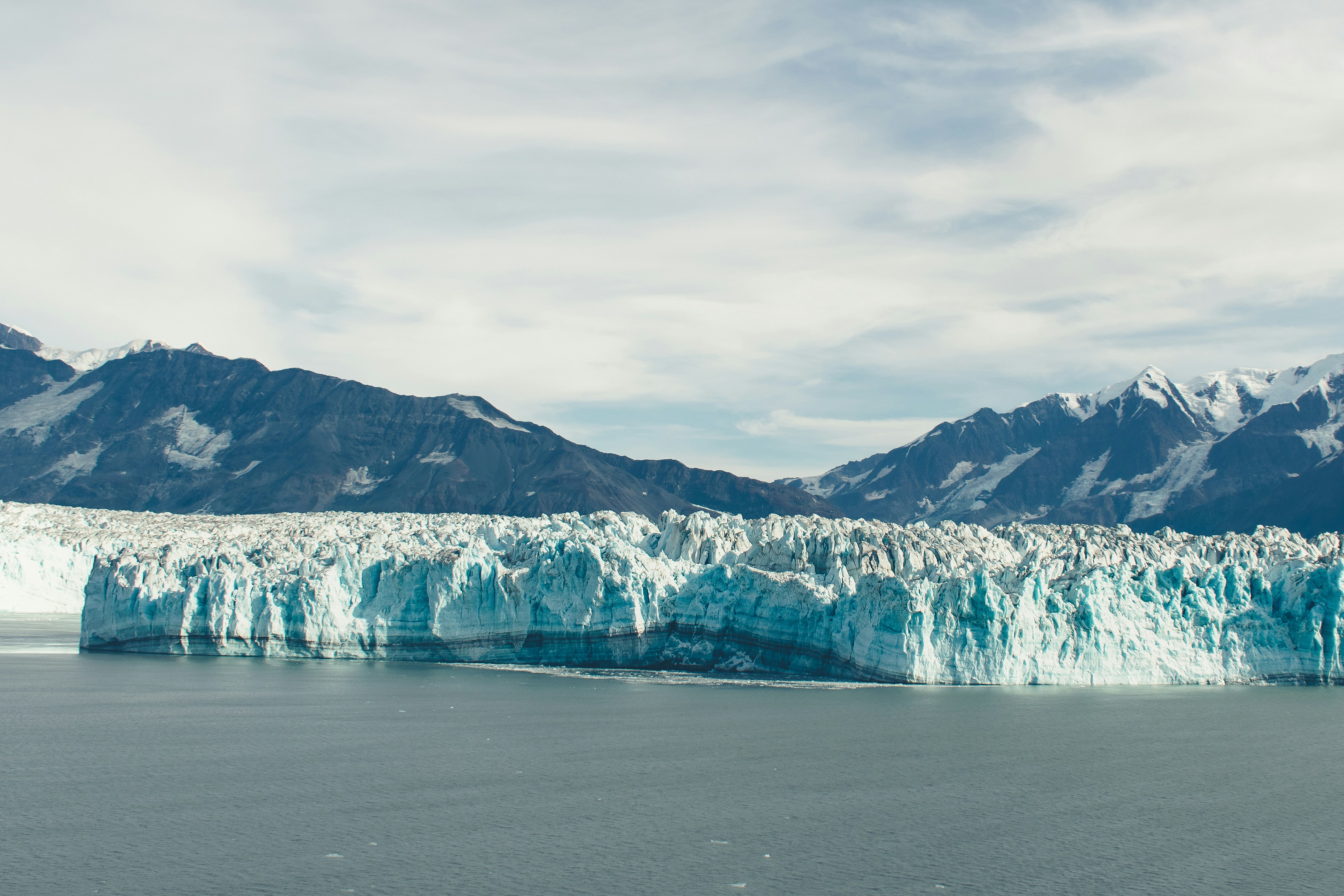 a large glacier with mountains in the background