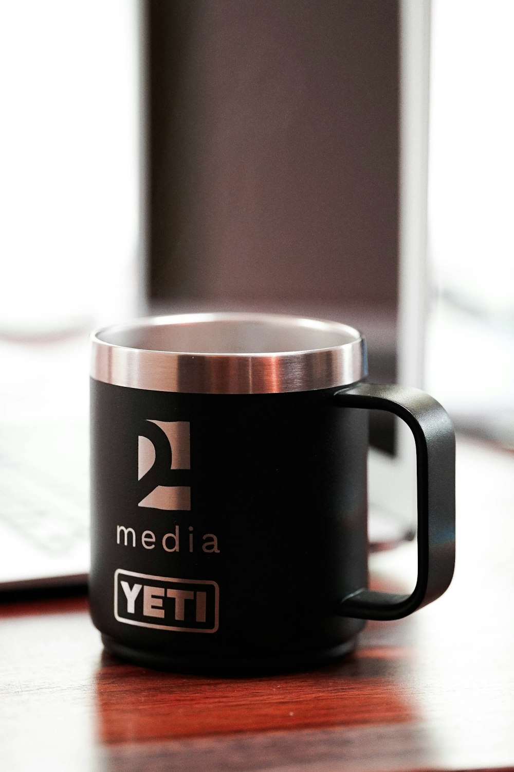 a black coffee mug sitting on top of a wooden table