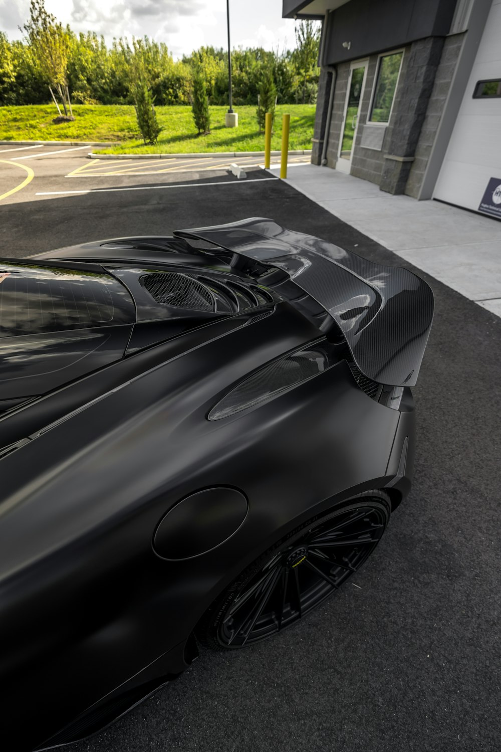 Une voiture de sport noire garée devant un immeuble