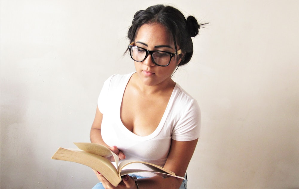 a woman wearing glasses is reading a book