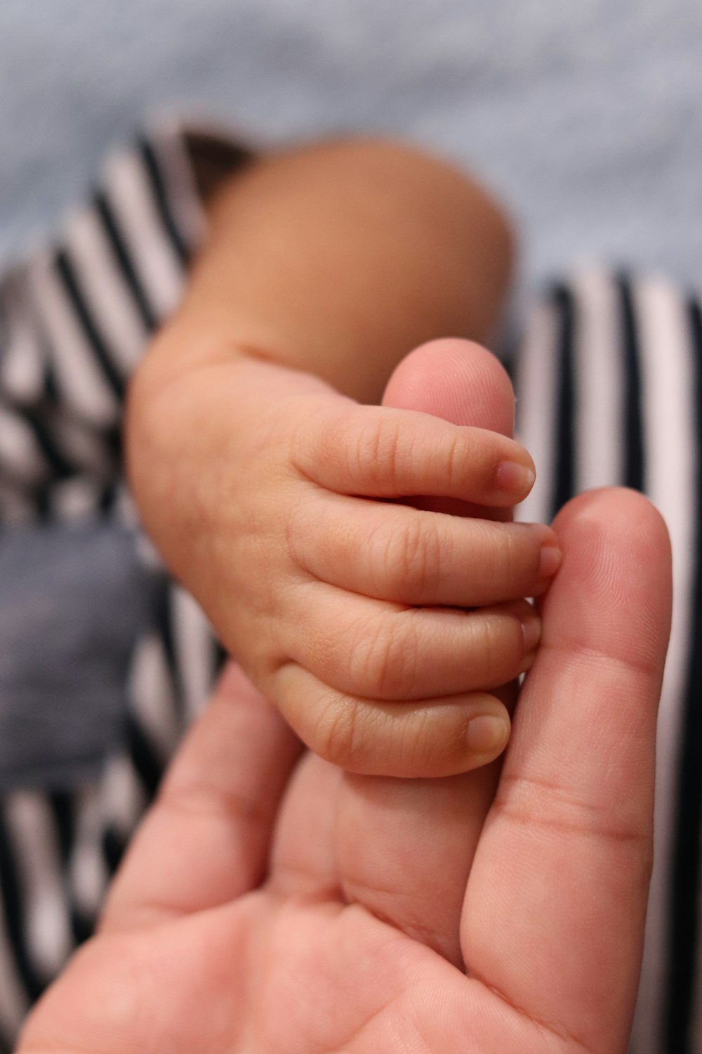 a person holding a baby's hand in their left hand