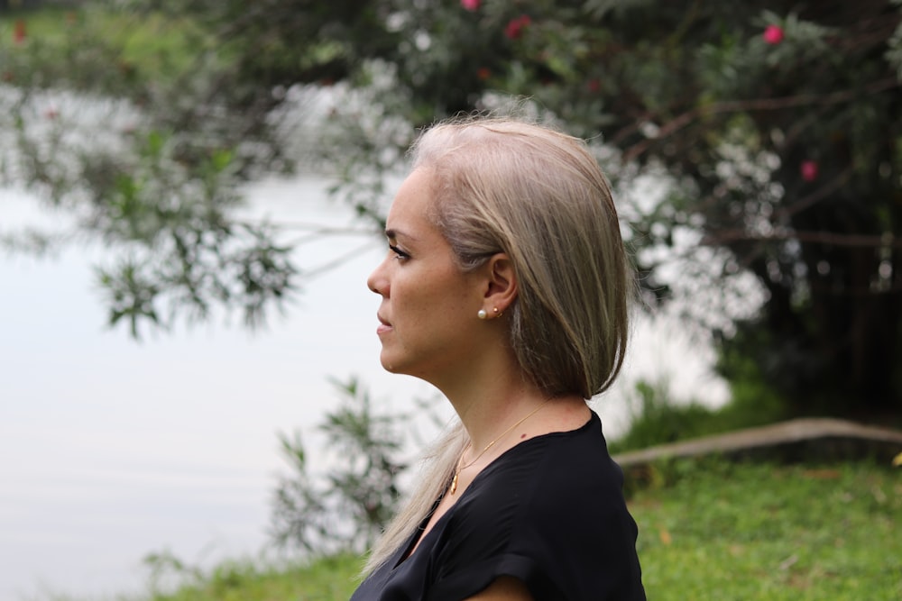 a woman with blonde hair standing in front of a body of water