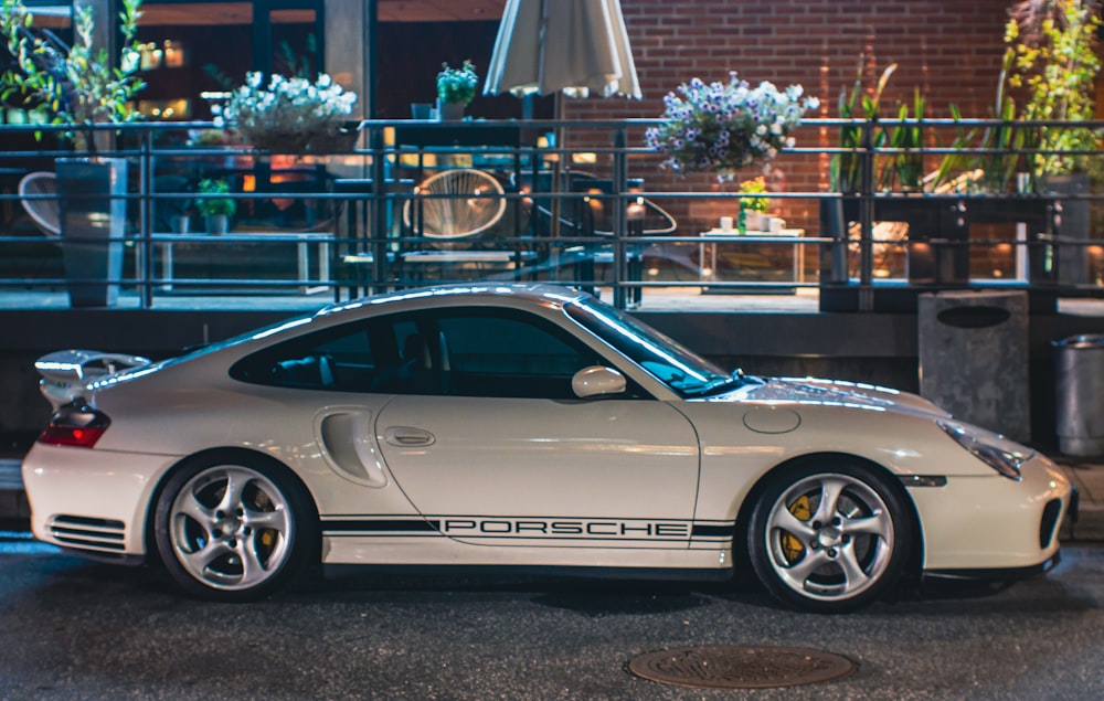 a white porsche parked in front of a building