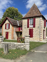 a stone house with red shutters and a stone fence