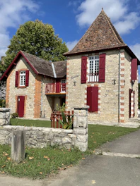 a stone house with red shutters and a stone fence