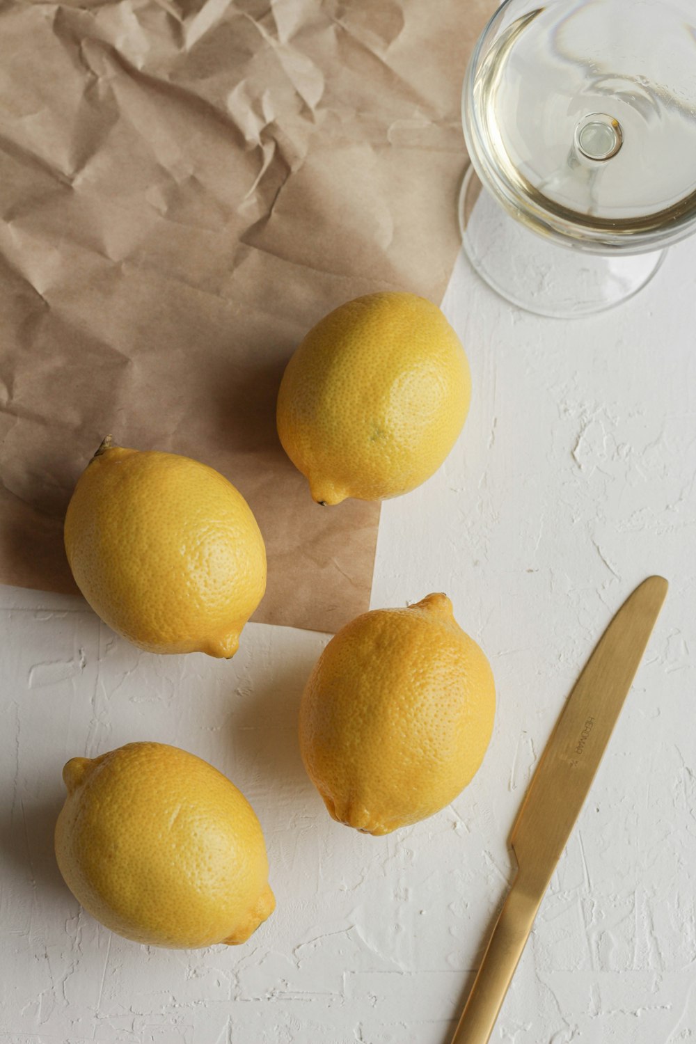 four lemons on a cutting board next to a knife