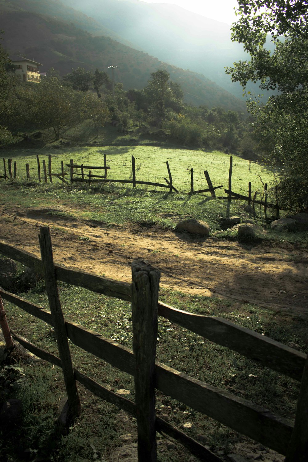 a field with a fence and a hill in the background