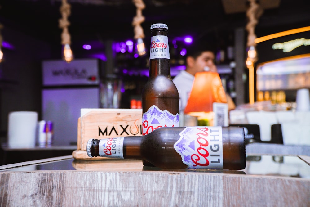 two bottles of beer sitting on top of a wooden table