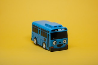a blue toy bus sitting on top of a yellow surface