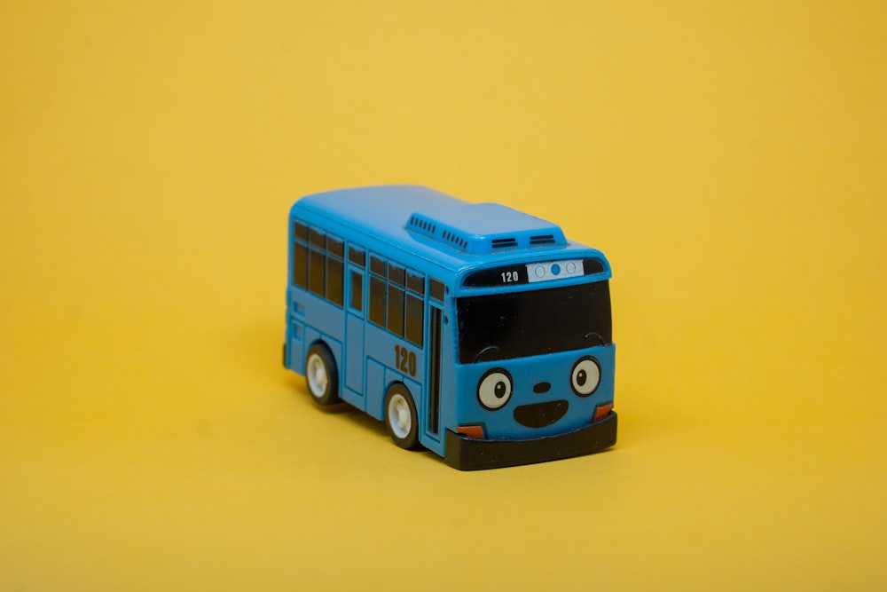 un bus jouet bleu assis sur une surface jaune