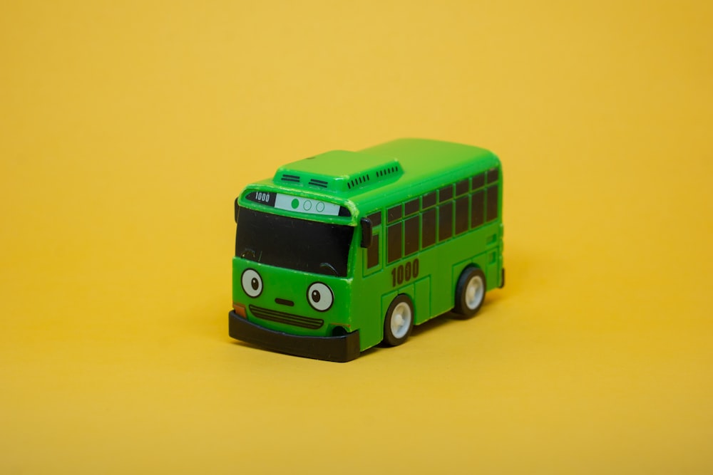 黄色の背景に緑のおもちゃのバス