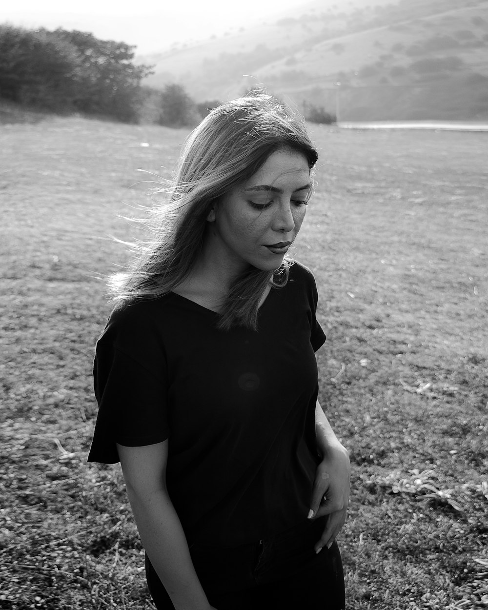 a woman standing in a field with her hand on her hip